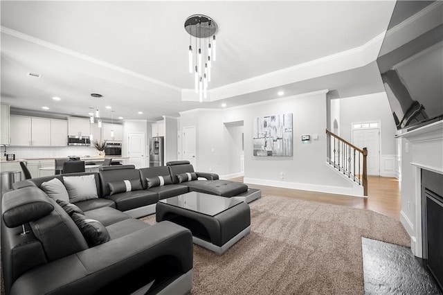 living area with stairway, recessed lighting, light wood finished floors, crown molding, and a fireplace with flush hearth
