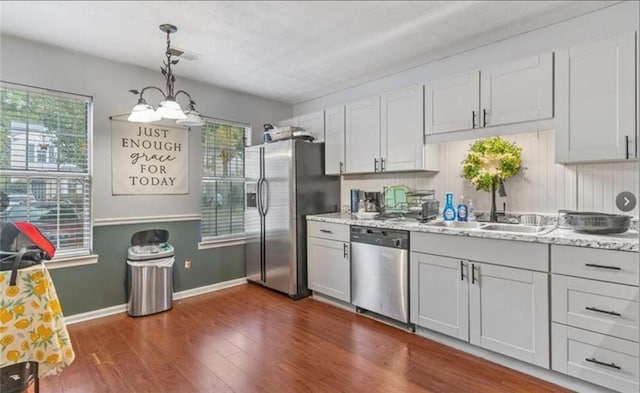 kitchen featuring stainless steel appliances, white cabinetry, hanging light fixtures, and a wealth of natural light