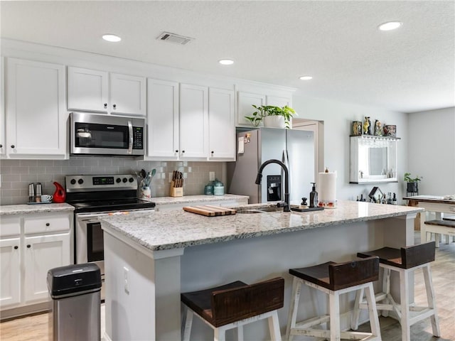 132 Mcmillian Ct, Winder, GA 30680 - kitchen featuring stainless steel appliances, white cabinetry, a kitchen bar, and recessed lighting