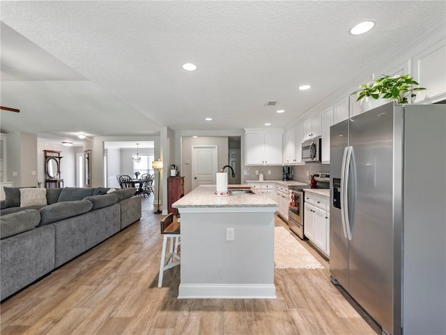 132 Mcmillian Ct, Winder, GA 30680 - kitchen with appliances with stainless steel finishes, open floor plan, a sink, white cabinets, and recessed lighting