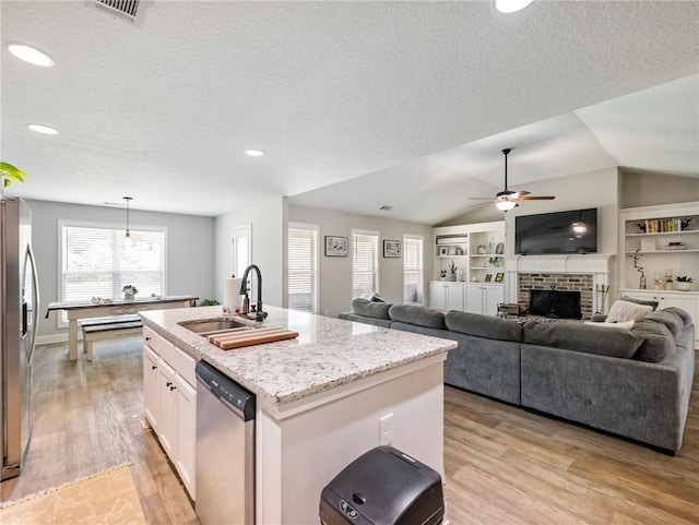 132 Mcmillian Ct, Winder, GA 30680 - kitchen featuring stainless steel appliances, light wood-style flooring, a sink, a center island with sink, and a textured ceiling