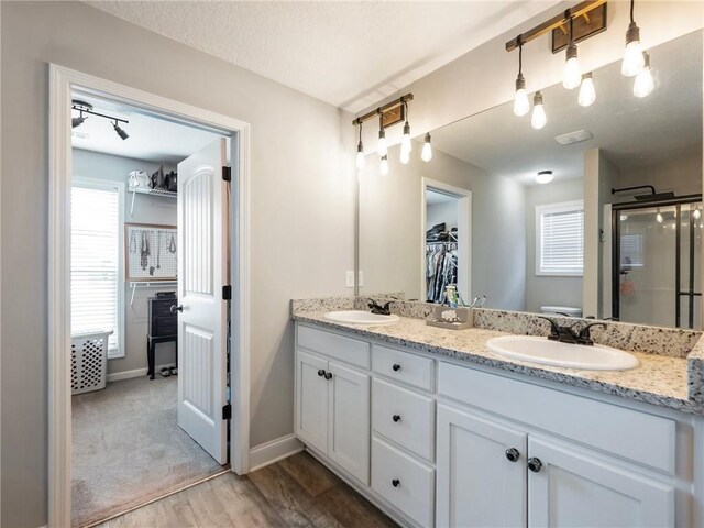 132 Mcmillian Ct, Winder, GA 30680 - full bath featuring double vanity, wood finished floors, a shower stall, baseboards, and a walk in closet