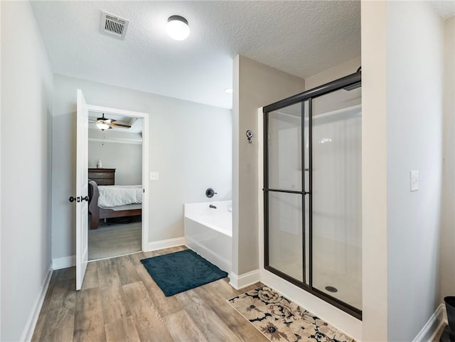 132 Mcmillian Ct, Winder, GA 30680 - ensuite bathroom featuring wood finished floors, a garden tub, a stall shower, ceiling fan, and a textured ceiling