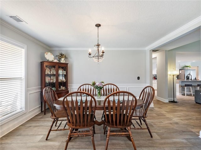 132 Mcmillian Ct, Winder, GA 30680 - dining space featuring a chandelier, light wood-type flooring, crown molding, and a wainscoted wall