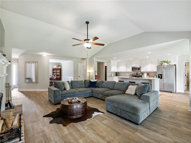 132 Mcmillian Ct, Winder, GA 30680 - living room featuring vaulted ceiling, light wood-style flooring, a ceiling fan, and baseboards
