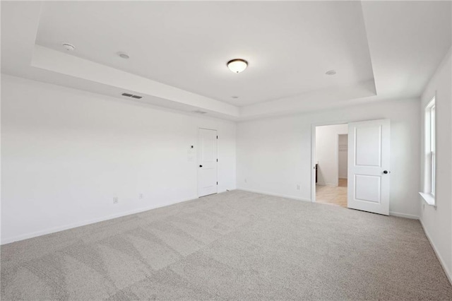 carpeted empty room with a raised ceiling