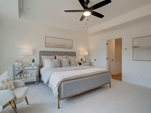 carpeted bedroom with ceiling fan and a raised ceiling