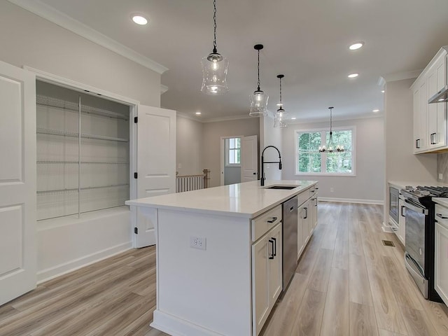 kitchen with pendant lighting, sink, white cabinets, a center island with sink, and stainless steel appliances