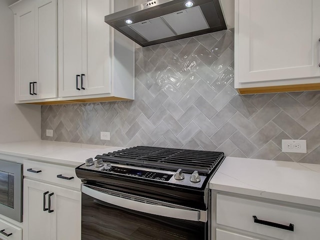 kitchen featuring built in microwave, tasteful backsplash, white cabinetry, wall chimney range hood, and stainless steel range with gas cooktop