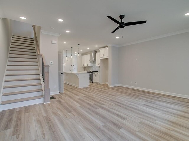 unfurnished living room with sink, ceiling fan, ornamental molding, and light hardwood / wood-style floors