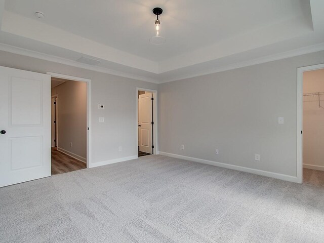 carpeted empty room with ornamental molding and a tray ceiling