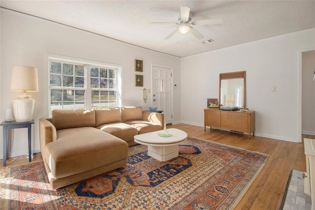 living room featuring baseboards, a textured ceiling, a ceiling fan, and hardwood / wood-style flooring