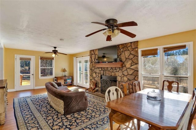 dining room with a stone fireplace, a textured ceiling, and light wood-type flooring