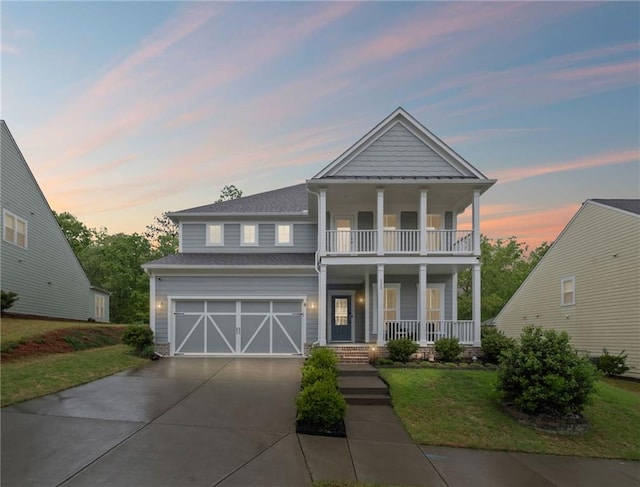 view of front of home featuring covered porch, driveway, a balcony, an attached garage, and a yard