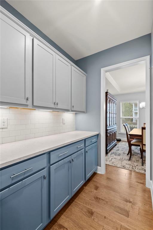 bar area featuring light wood-style floors, backsplash, and baseboards