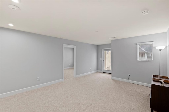 spare room featuring baseboards, light carpet, and a smoke detector
