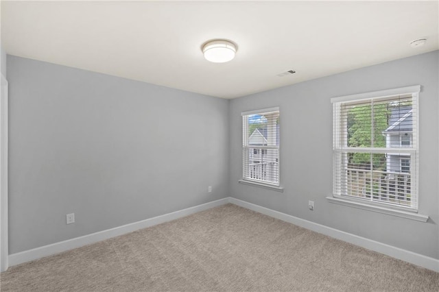 carpeted empty room featuring healthy amount of natural light and baseboards