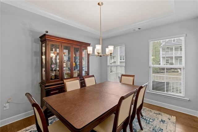 dining area with a chandelier, baseboards, wood finished floors, and a tray ceiling