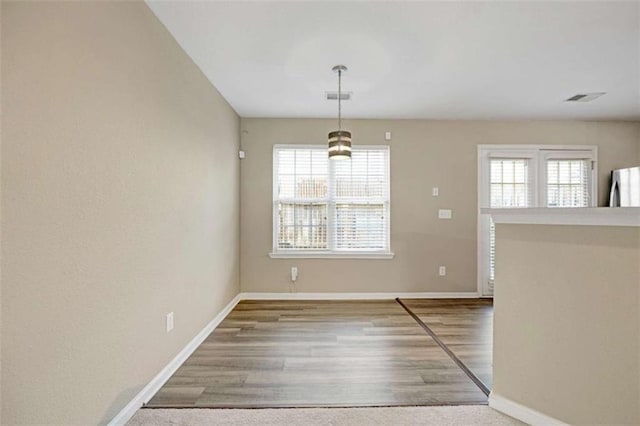 unfurnished dining area with hardwood / wood-style flooring and plenty of natural light