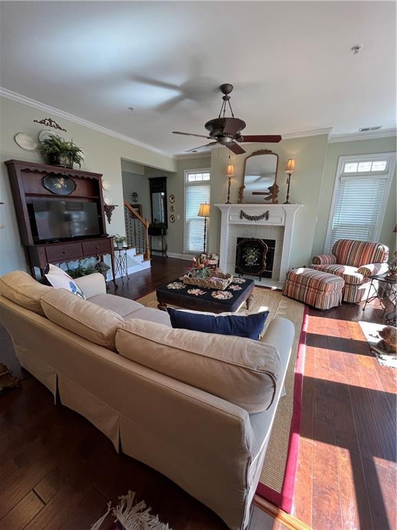 living room with hardwood / wood-style flooring, crown molding, and a tile fireplace