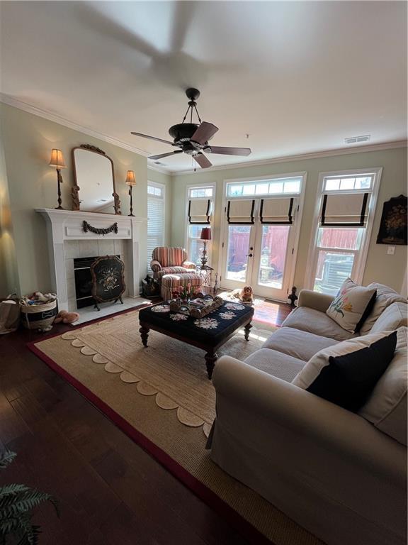 living area with hardwood / wood-style floors, crown molding, a fireplace, and visible vents