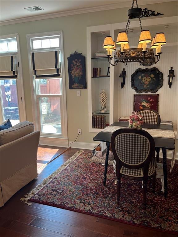 dining room with crown molding, a notable chandelier, visible vents, and wood-type flooring