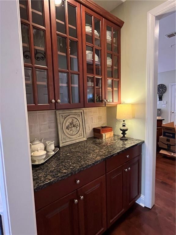 bar with dark wood finished floors, visible vents, and decorative backsplash