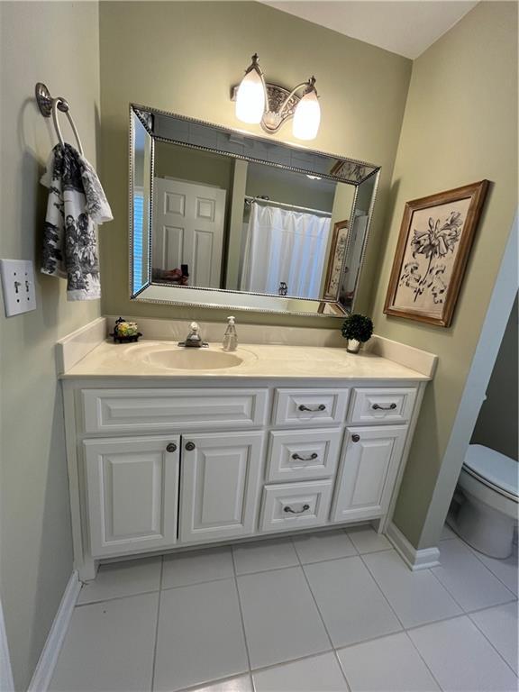 full bath with tile patterned flooring, toilet, vanity, and baseboards