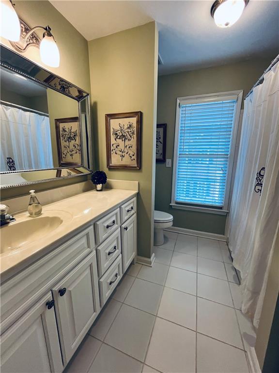 bathroom featuring vanity, tile patterned floors, toilet, and baseboards