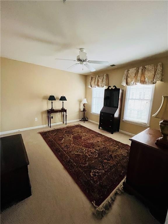 living room featuring a ceiling fan, baseboards, and carpet floors