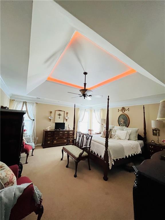 carpeted bedroom with a tray ceiling and ornamental molding