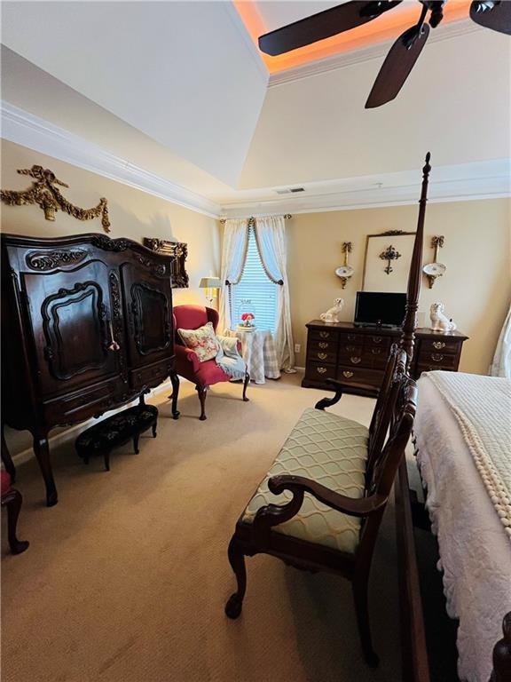 carpeted bedroom featuring lofted ceiling, ornamental molding, visible vents, and ceiling fan