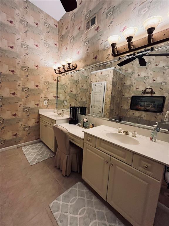 bathroom with tile patterned floors, wallpapered walls, baseboards, ceiling fan, and vanity