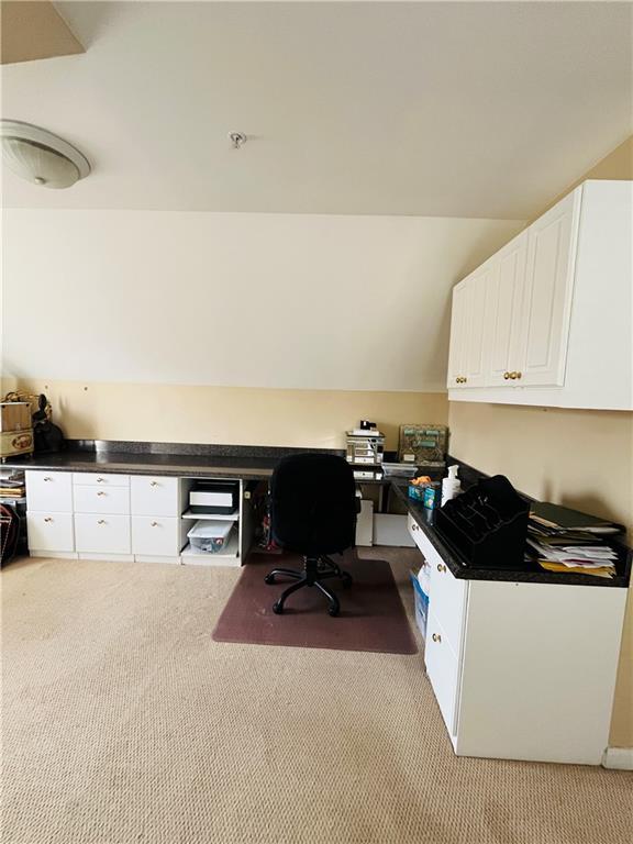 office space with light carpet, built in desk, and vaulted ceiling