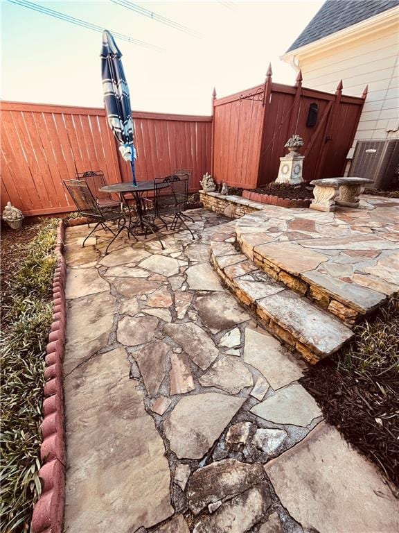 view of patio / terrace with outdoor dining area, central air condition unit, and fence