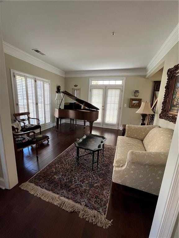 living area with hardwood / wood-style floors, crown molding, baseboards, and visible vents