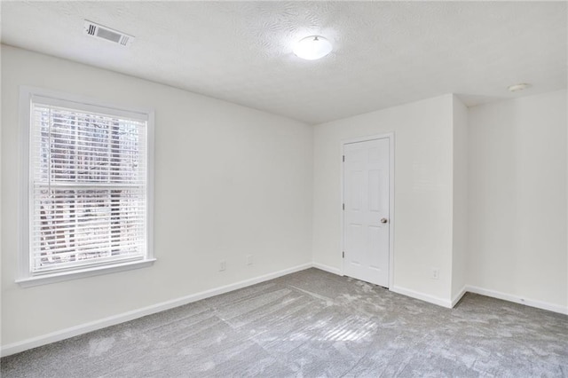 carpeted empty room featuring a textured ceiling