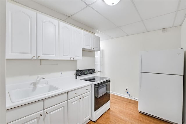 kitchen featuring white appliances, a drop ceiling, sink, and white cabinets