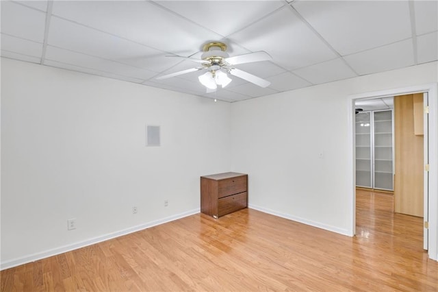 unfurnished room featuring a drop ceiling, ceiling fan, and light wood-type flooring