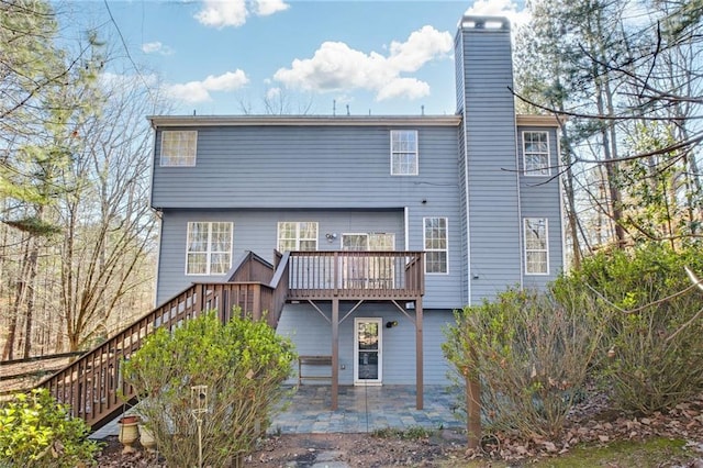 rear view of house with a wooden deck and a patio area