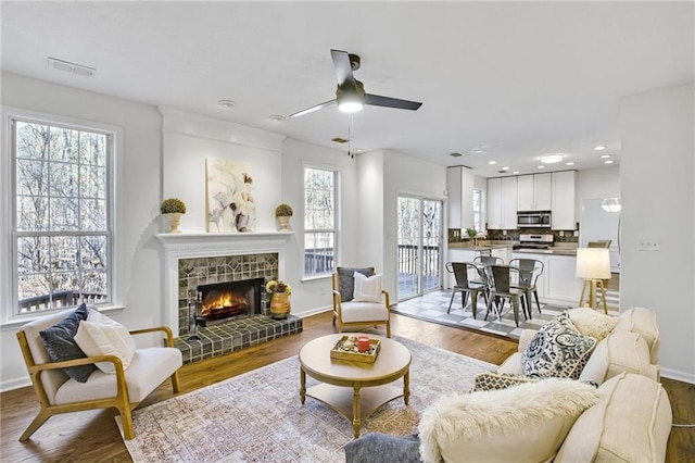 living room with a fireplace, wood-type flooring, sink, and ceiling fan