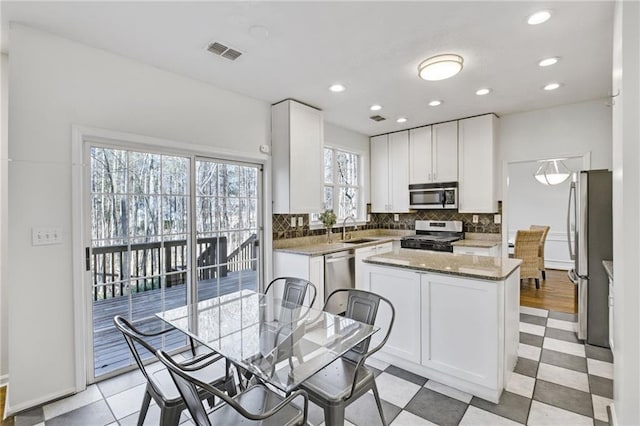 kitchen with sink, white cabinets, backsplash, dark stone counters, and stainless steel appliances