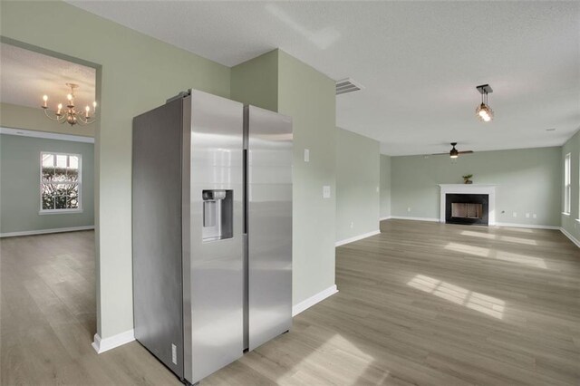 kitchen with ceiling fan with notable chandelier, light wood-type flooring, and stainless steel refrigerator with ice dispenser