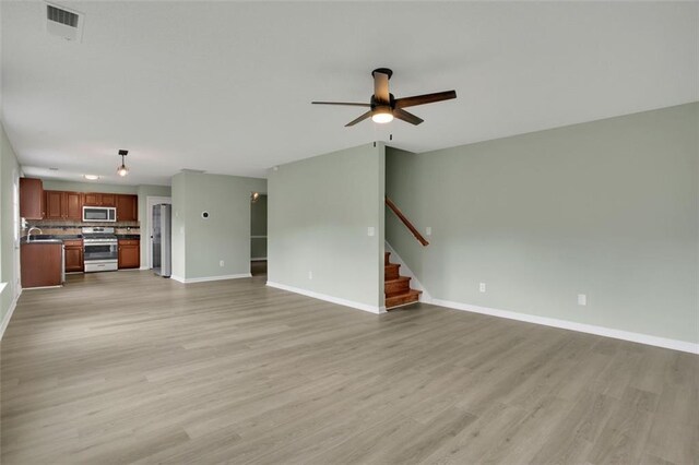 unfurnished living room with light wood-type flooring, sink, and ceiling fan