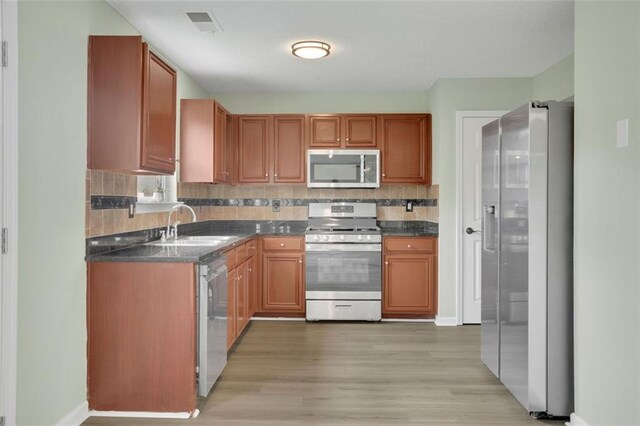 kitchen featuring decorative backsplash, sink, light hardwood / wood-style flooring, and stainless steel appliances