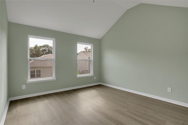 unfurnished room with lofted ceiling and hardwood / wood-style flooring