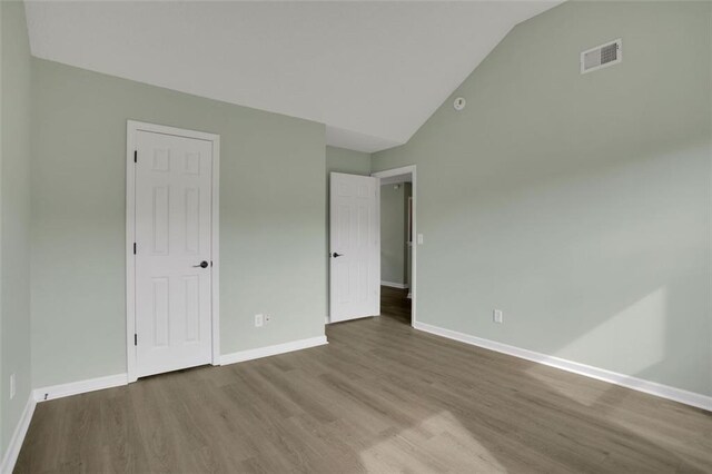 unfurnished bedroom with hardwood / wood-style flooring and vaulted ceiling