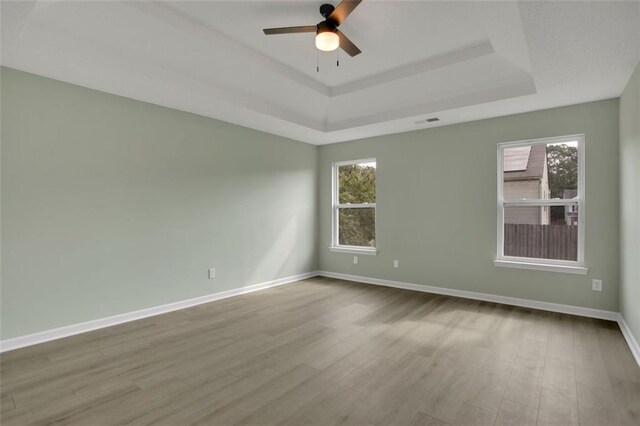 unfurnished room with light hardwood / wood-style flooring, a tray ceiling, and ceiling fan