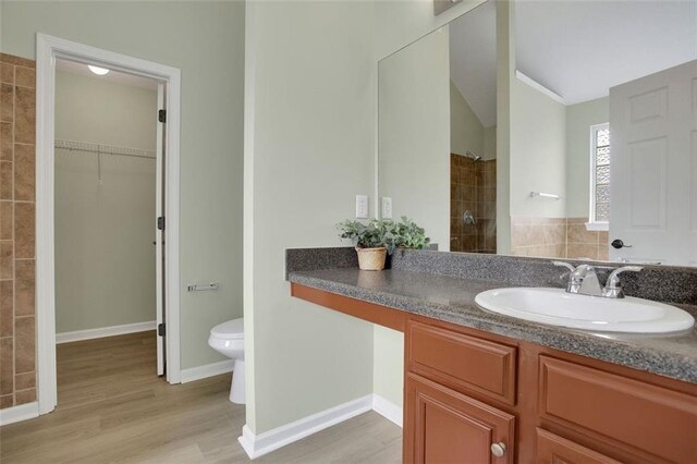 bathroom with a shower, vanity, wood-type flooring, lofted ceiling, and toilet