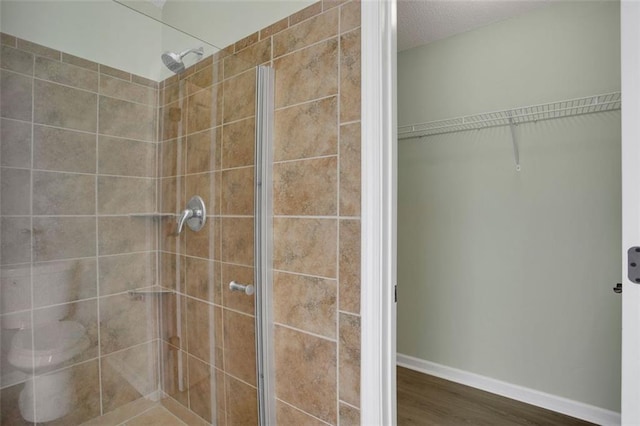 bathroom featuring a tile shower, hardwood / wood-style floors, and toilet